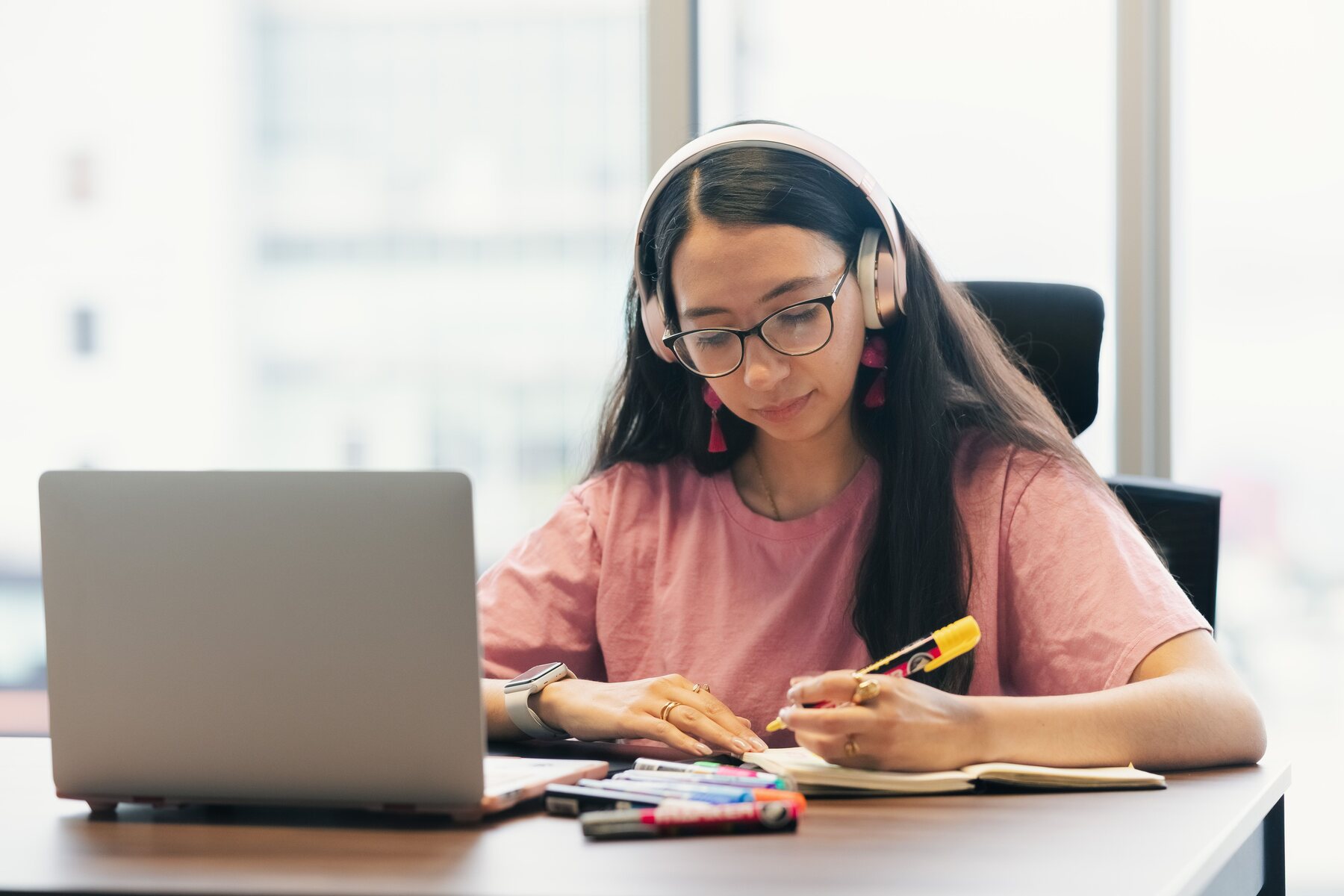 Fejhallgatós tanuló jegyzetel laptop mellett egy online nyelvórán